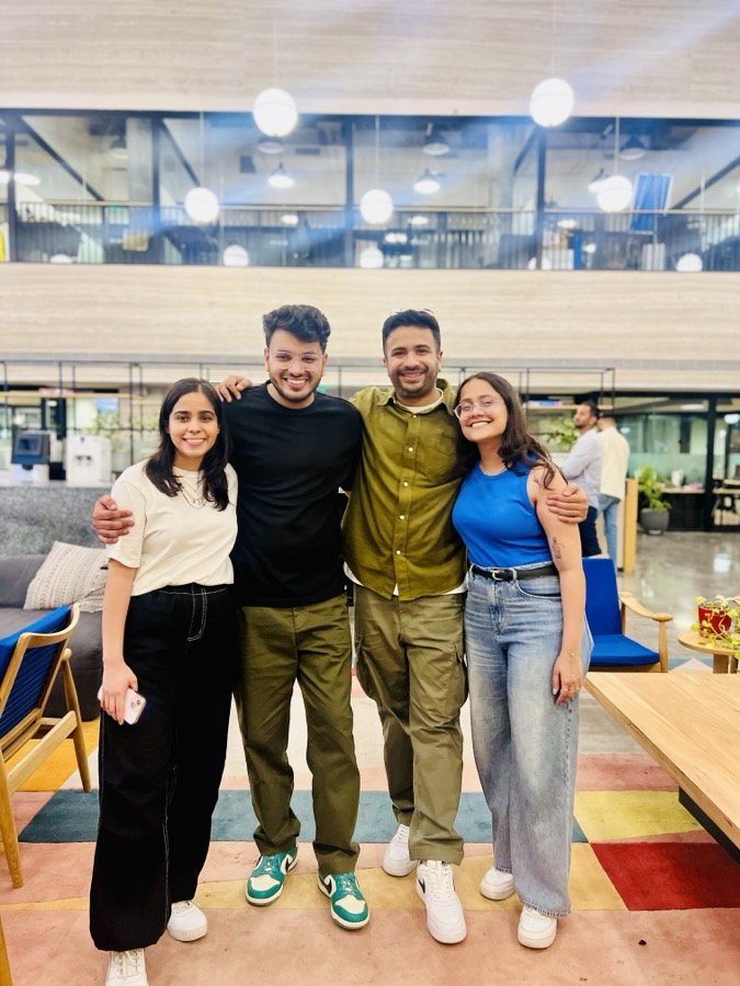 Manik Madaan and three former colleagues, arms around each other, in their office.